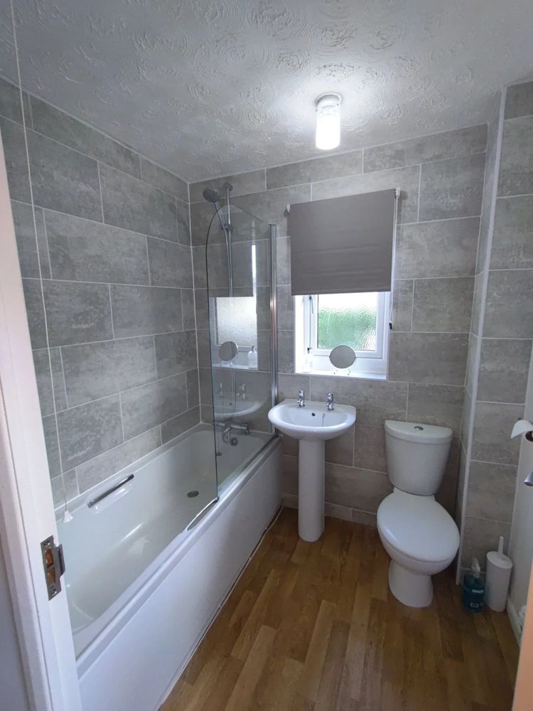 Tiled bathroom with bath, shower screen, basin and toilet