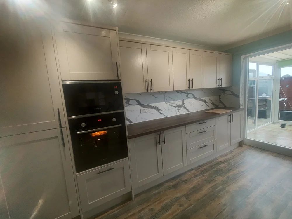 Cream shaker kitchen with marble splashback, built-in oven and dark worktop