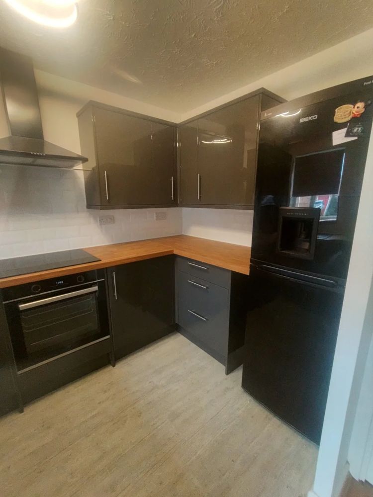 Dark gloss kitchen with oak worktop and black appliances