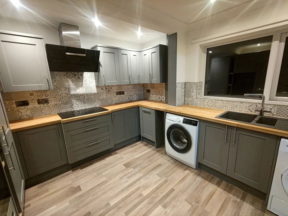 Grey shaker kitchen with patterned tile splashback and oak worktop