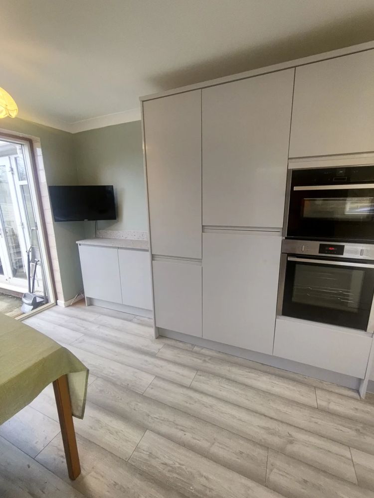 Light grey handleless kitchen with tall units and built-in ovens